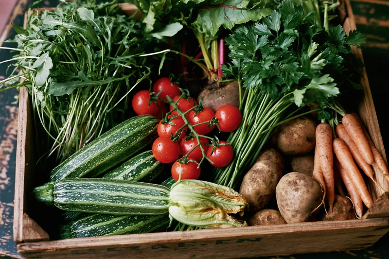 Vegetable crate bursting with fresh produce, greens, roots a
