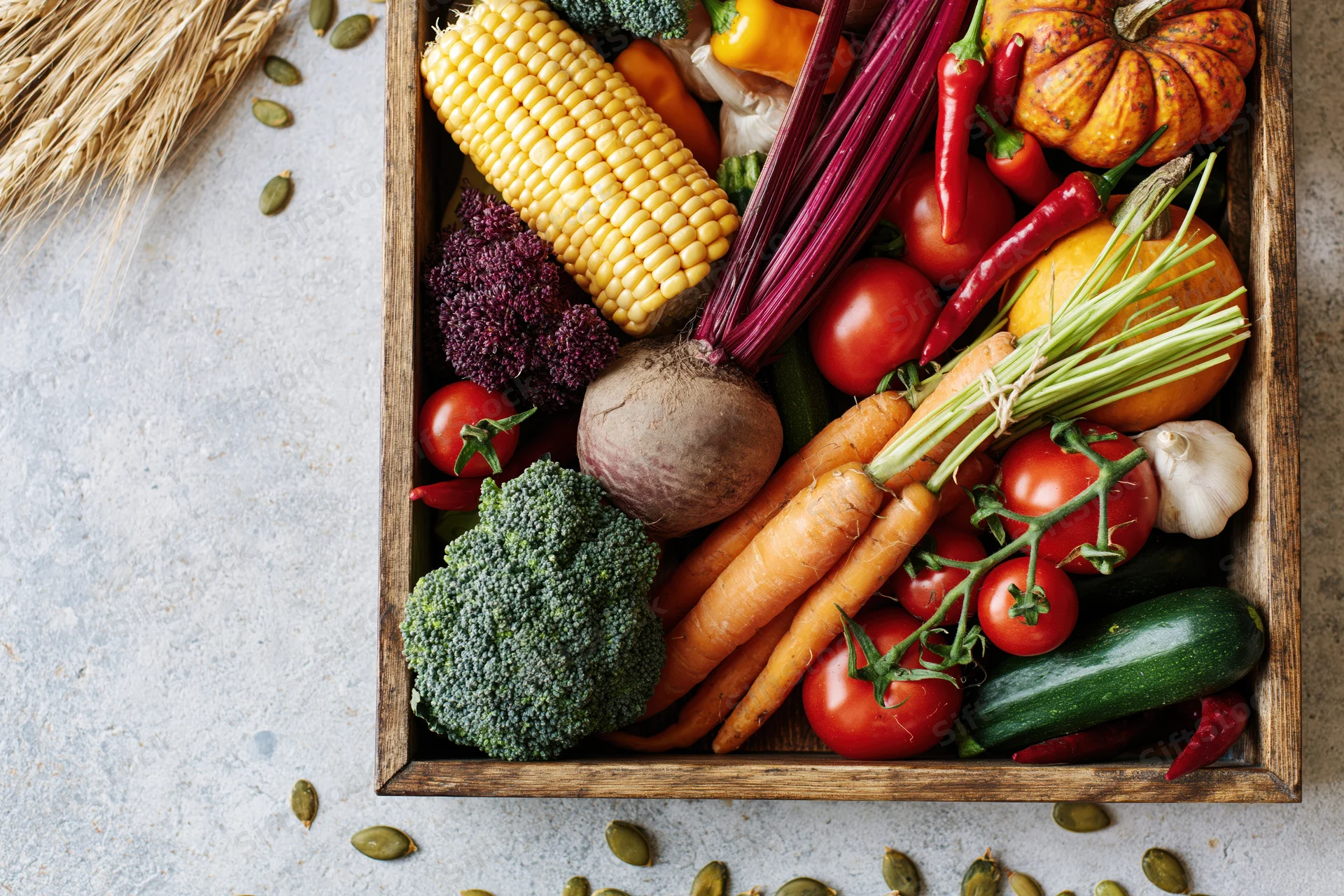 Wooden tray filled with fresh autumn harvest vegetables arranged on a light surface