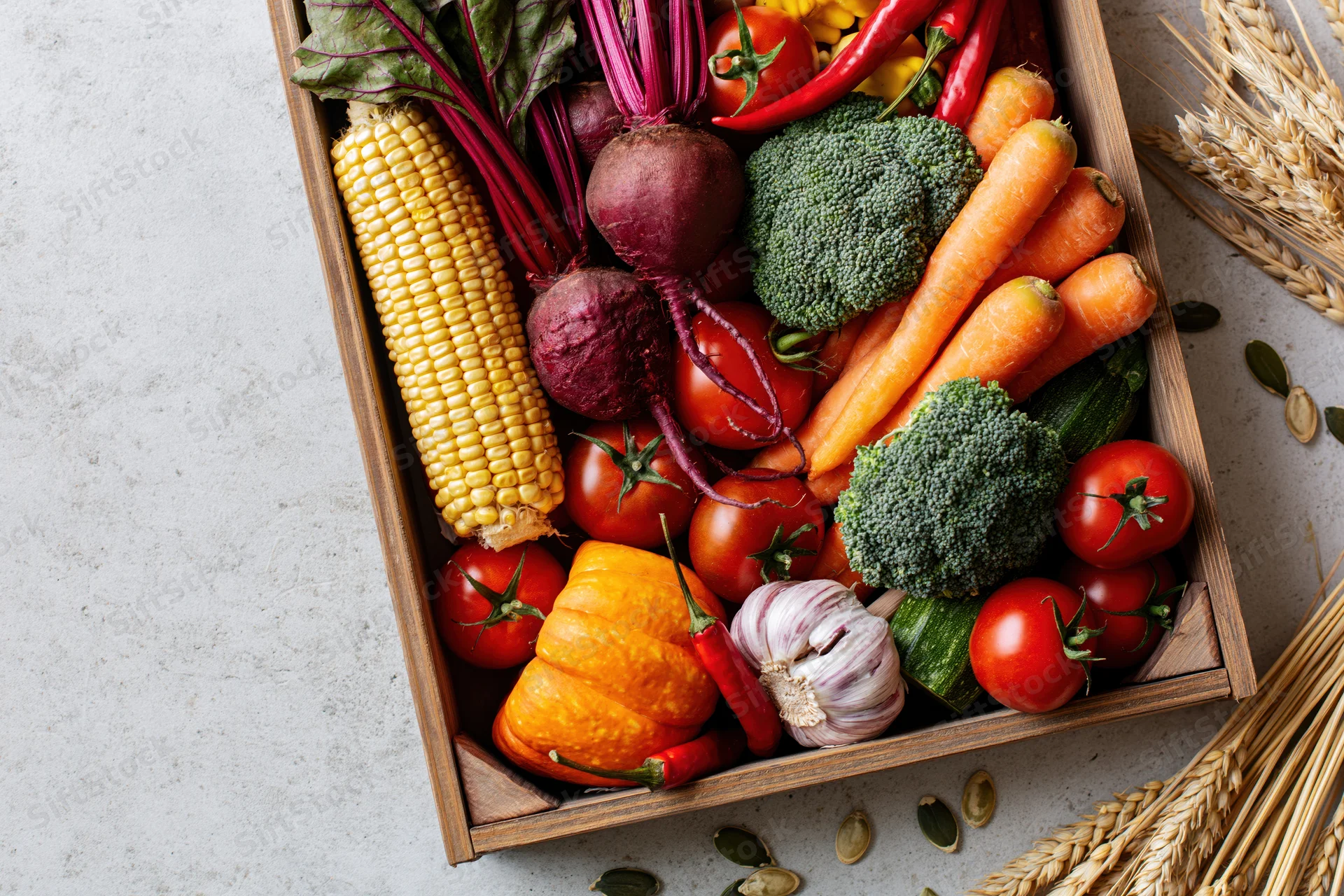 Wooden tray filled with fresh autumn harvest vegetables arranged on a light surface