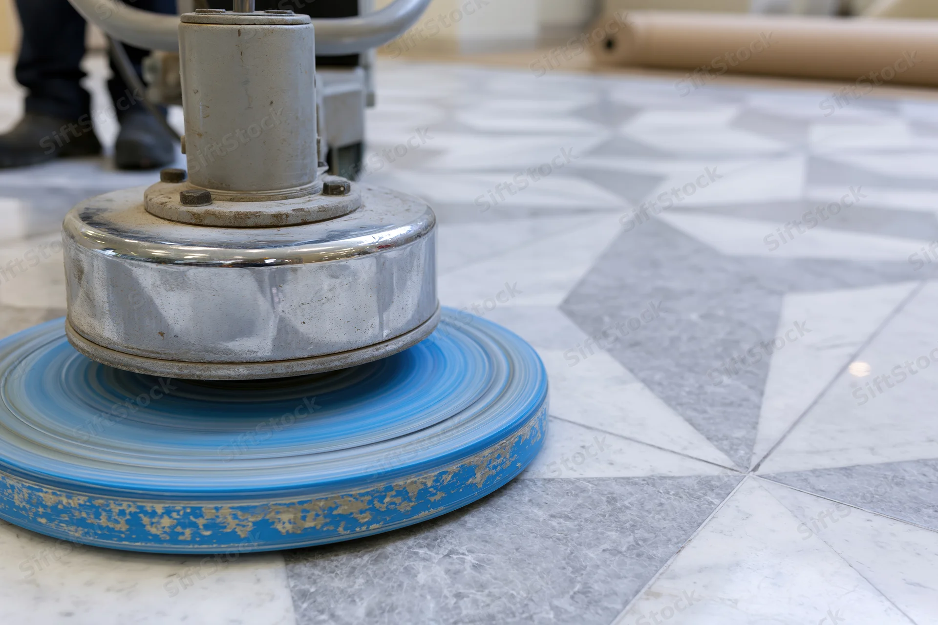 Commercial floor polishing machine with blue rotating pad on patterned tile floor