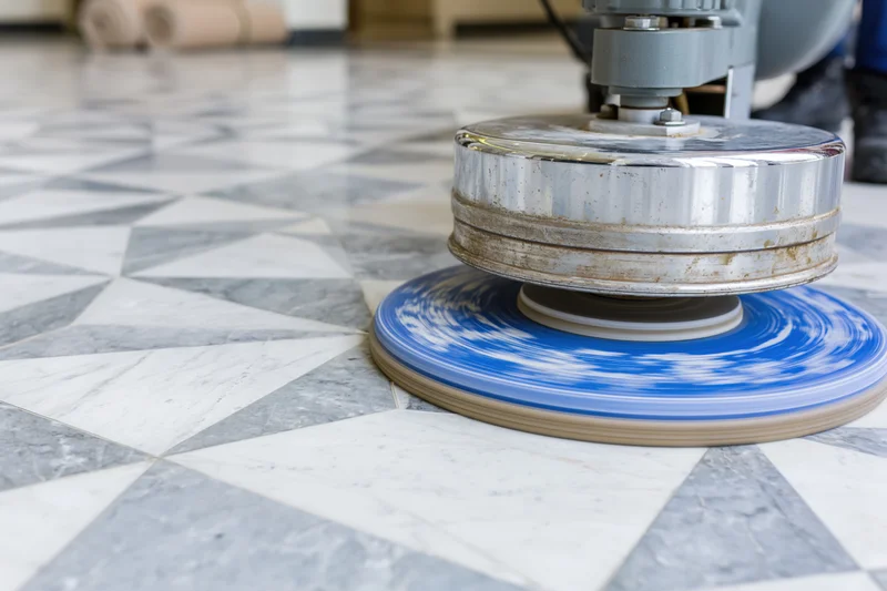 Commercial floor polishing machine with blue rotating pad operating on geometric tile floor
