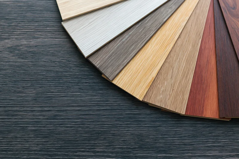 Fan arrangement of wood laminate flooring samples on dark textured surface