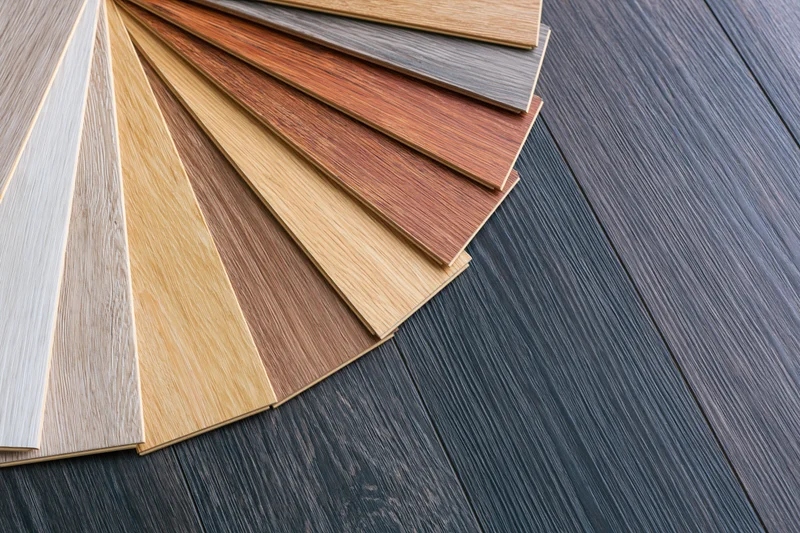 Fan arrangement of wood flooring laminate samples on dark floor surface
