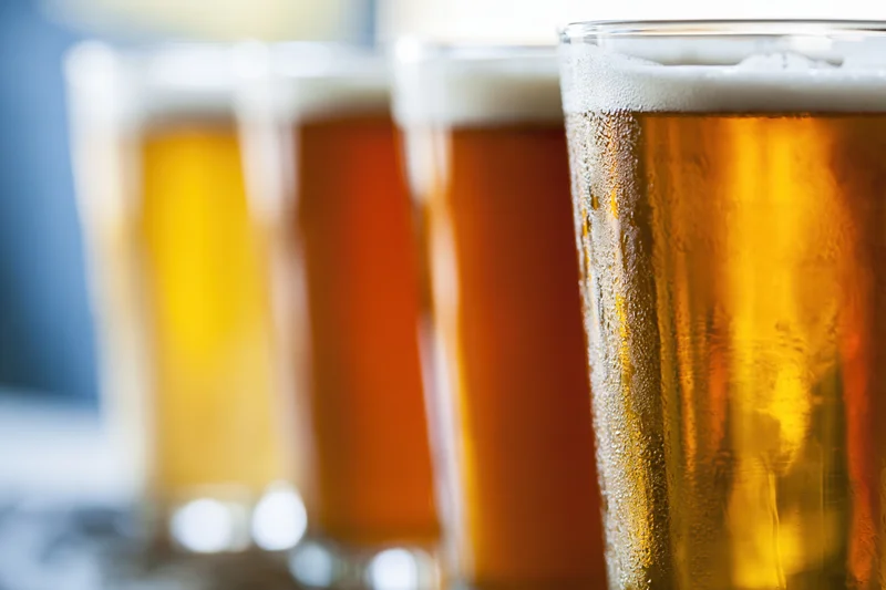 Four craft beer tasting glasses lined up in a row with condensation and foam, closeup view