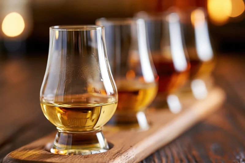 Whisky tasting flight of glasses arranged in a row on a wooden tray