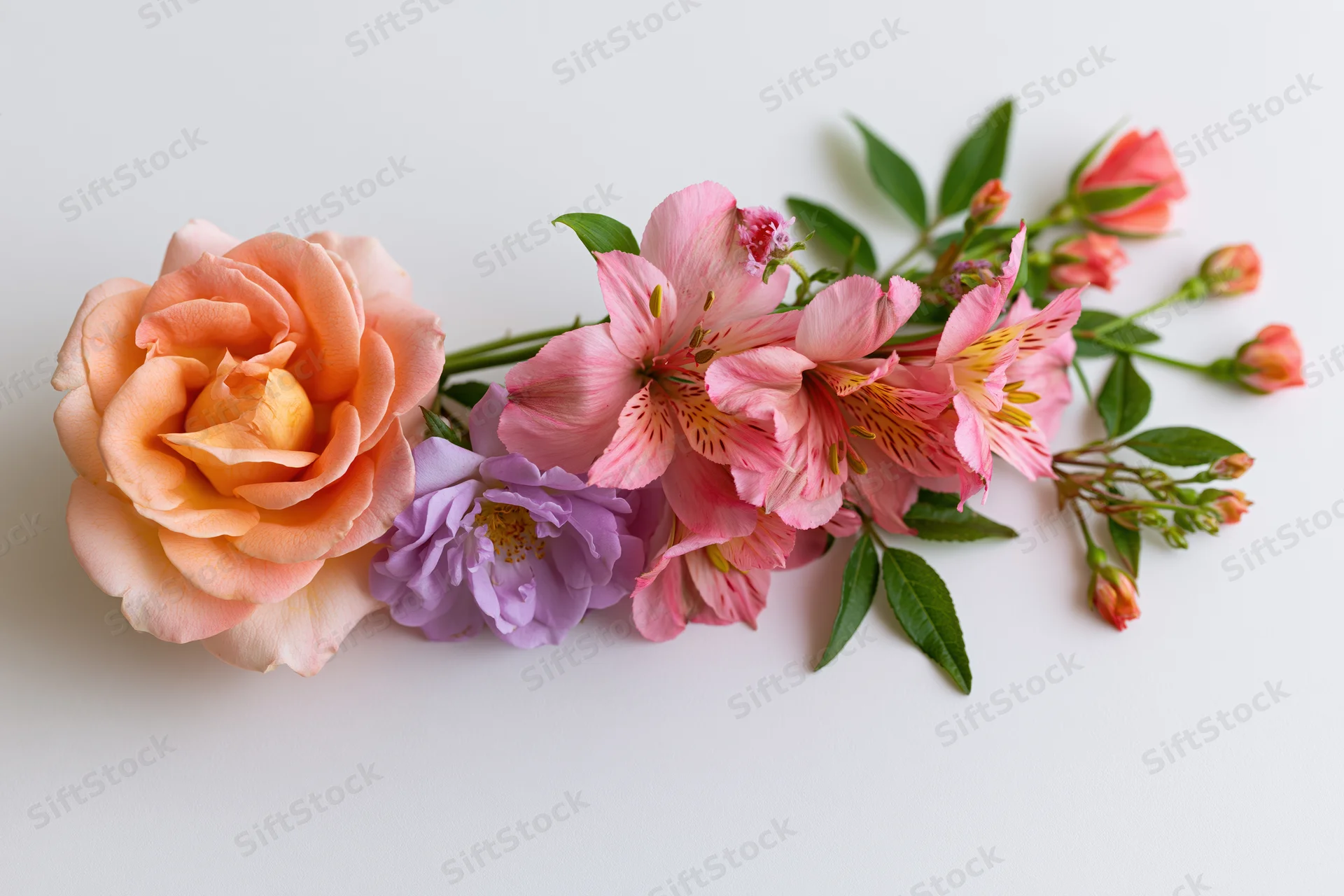 Curved floral arrangement lying flat on white background with roses, alstroemeria, and lavender blooms