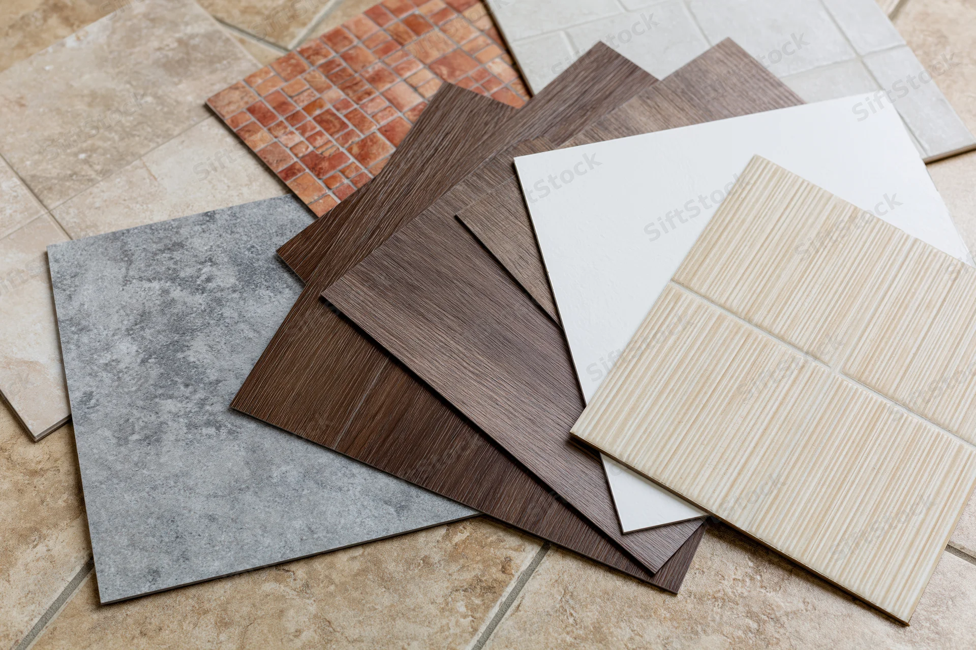 Flooring and tile sample squares fanned out on a tiled floor for selection and design planning
