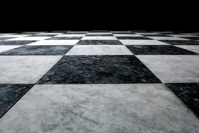 Aged black and white marble checkerboard floor extending into perspective with visible texture and wear