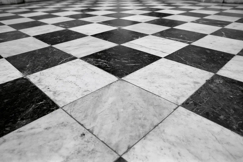 Aged black and white marble checkerboard floor tiles receding into perspective