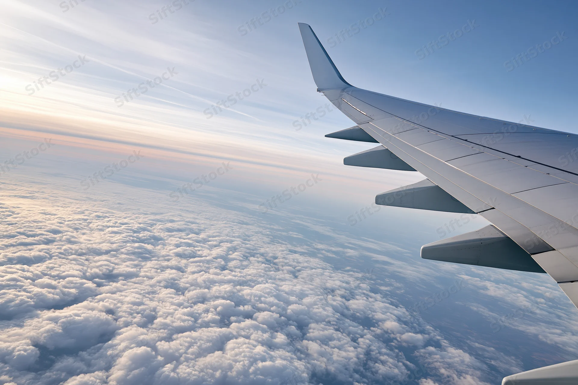 Airplane wing viewed from passenger window during cruising flight above cloud layer