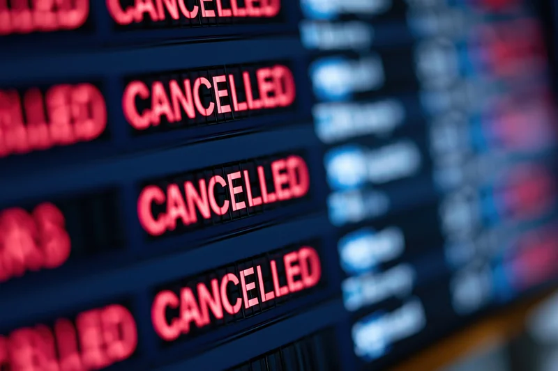 Digital departure board showing multiple cancelled flights in red text at airport terminal