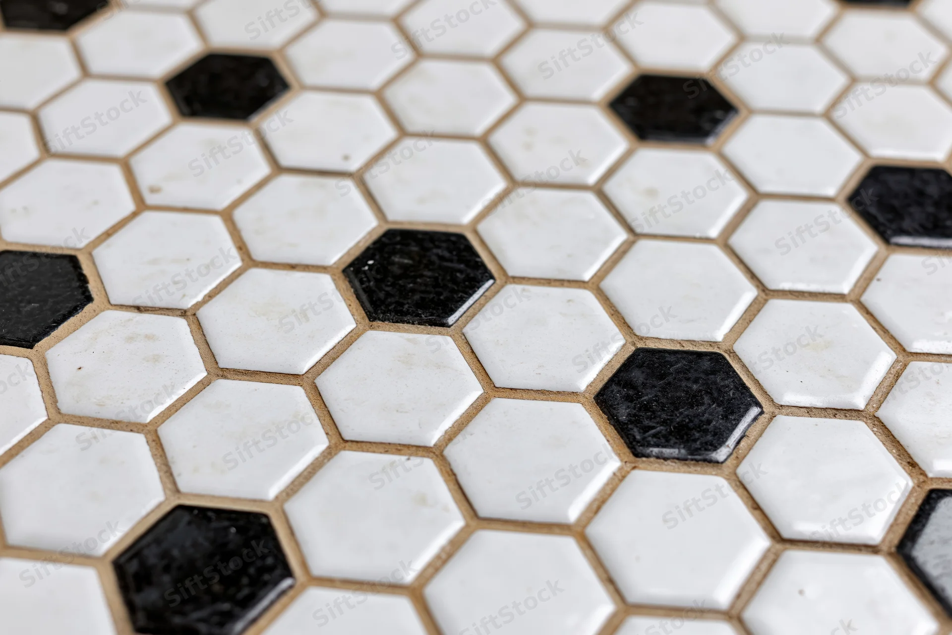 Hexagonal black and white ceramic tile floor arranged in a repeating pattern with grout lines visible