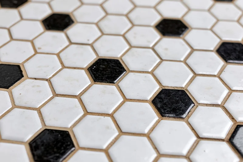 Hexagonal black and white ceramic tile floor arranged in a repeating pattern with grout lines visible