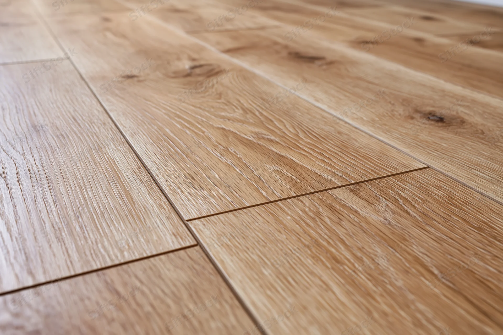 Close-up angled view of medium oak laminate flooring planks arranged in staggered pattern on interior floor