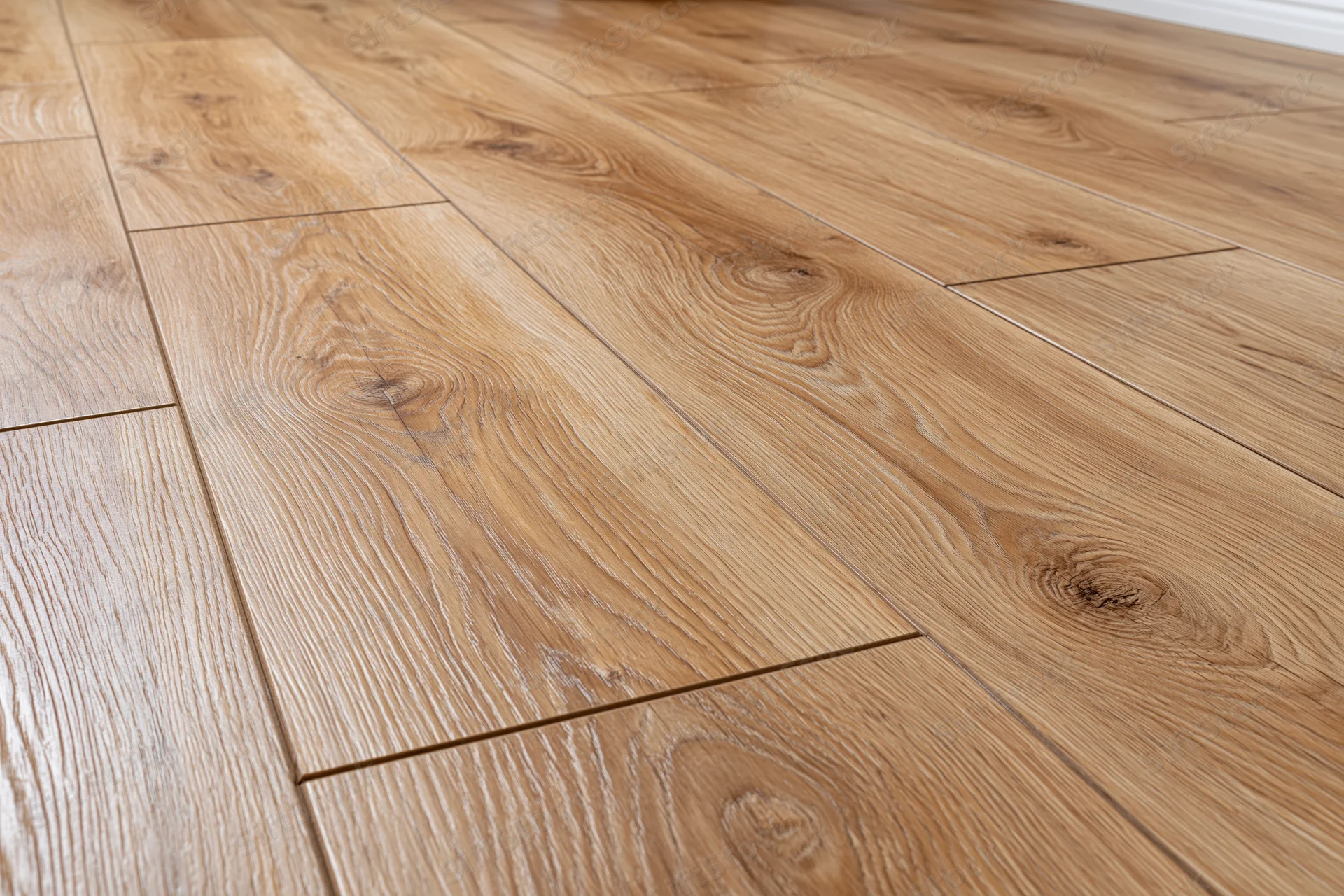 Medium oak laminate flooring planks arranged in staggered pattern on interior floor