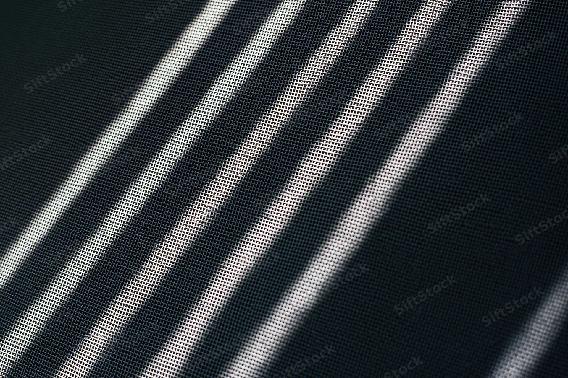 Close-up of dark grey window screen mesh with diagonal light patterns filling the frame