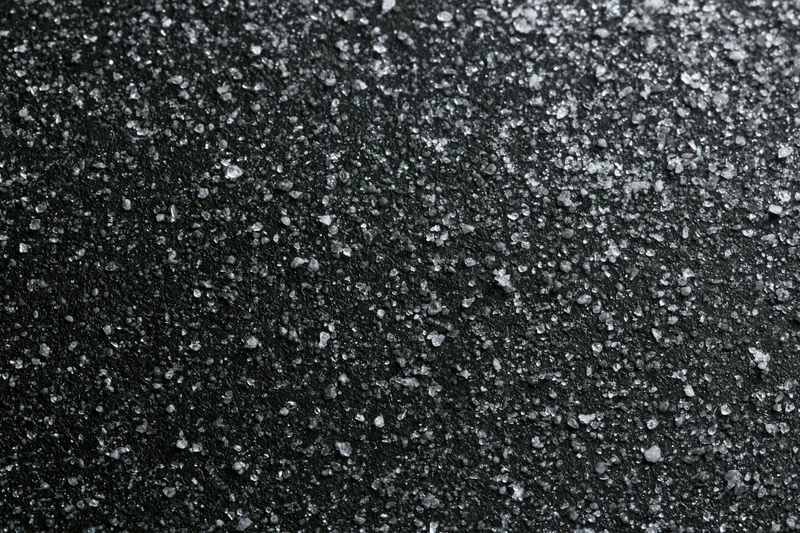 Close-up of dark matte black surface covered in fine crystalline particles arranged flatly