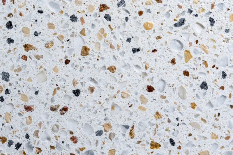 Polished terrazzo floor surface with embedded stone aggregates in white and earth tones, flat lay view