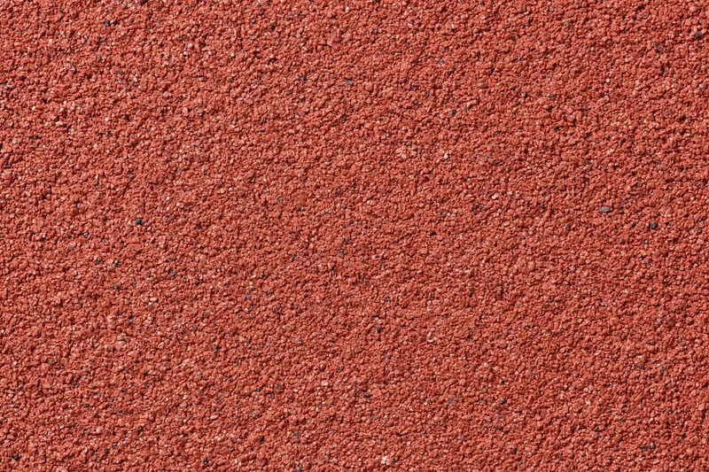 Close-up flat lay of a red rubber running track surface filling the frame