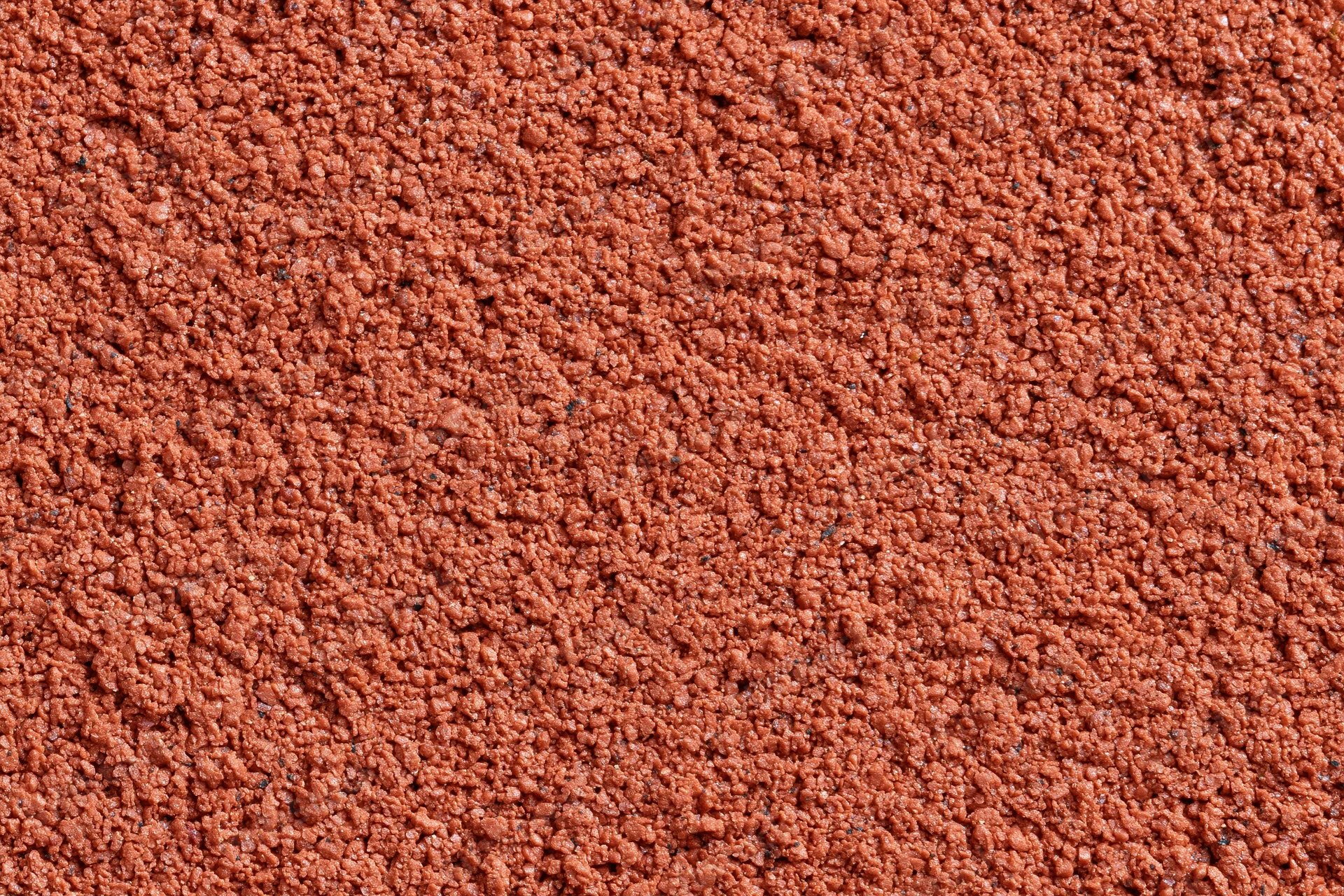 Close-up flat lay of a red rubber running track surface filling the frame