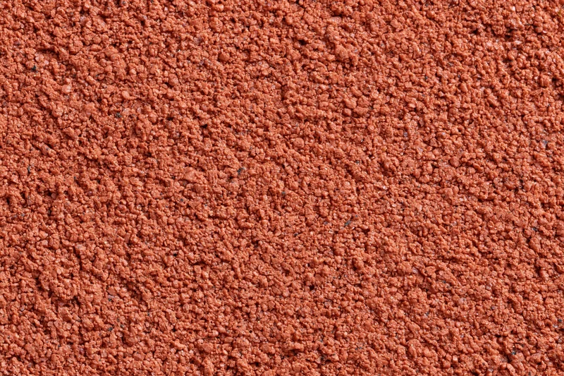 Close-up flat lay of a red rubber running track surface filling the frame