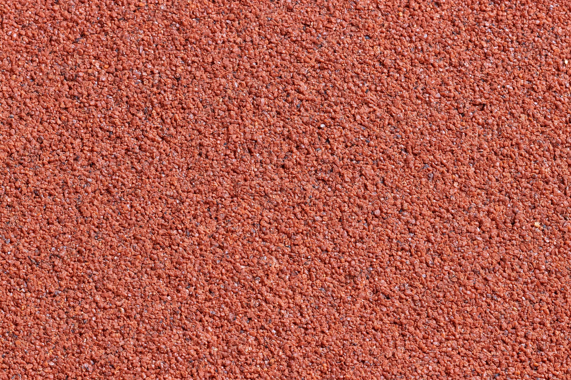 Close-up of red rubber running track surface filling the frame