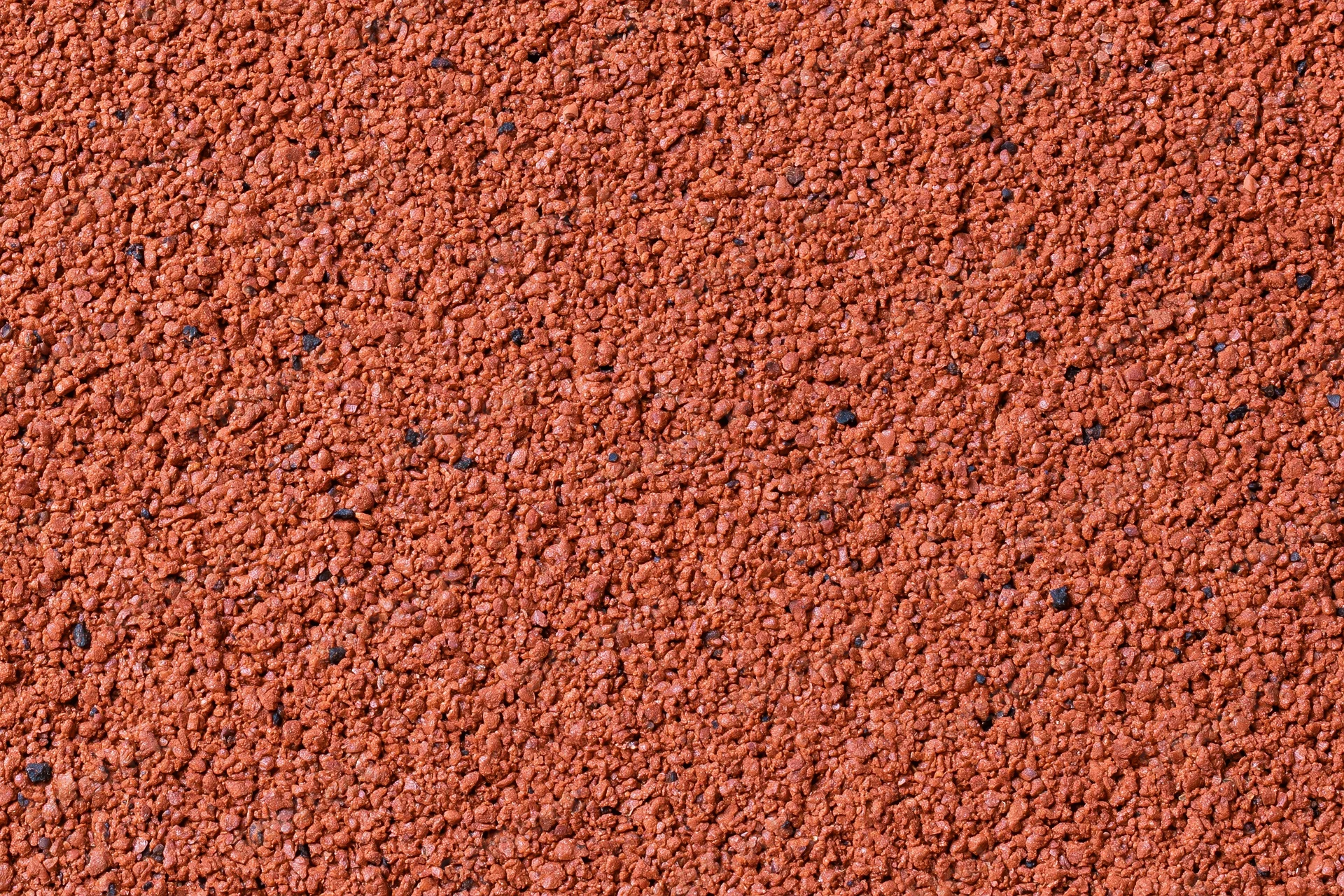 Close-up flat lay of a red rubber running track surface filling the frame