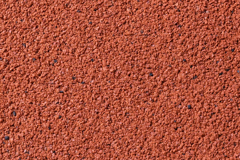 Close-up flat lay of a red rubber running track surface filling the frame
