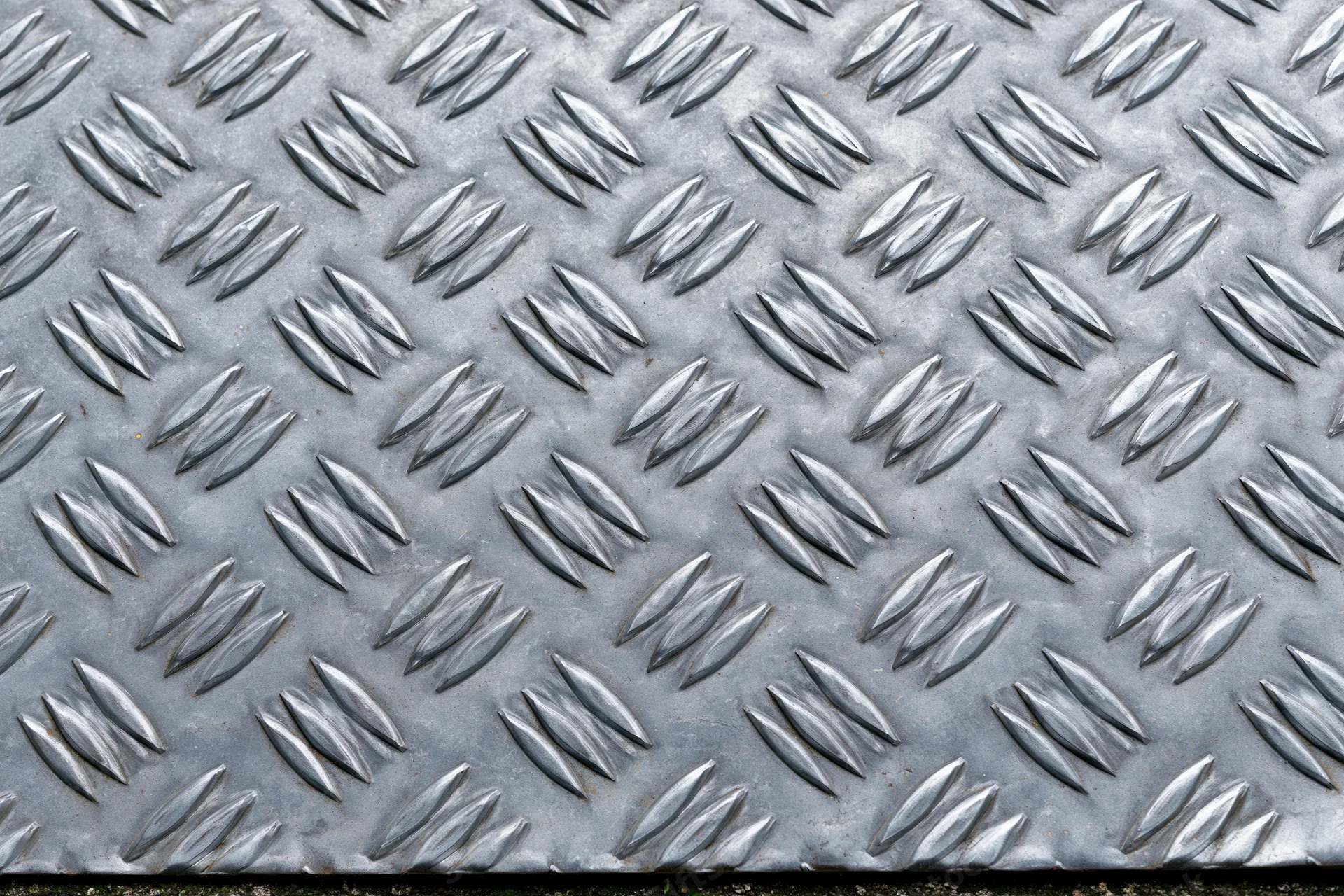 Close-up of steel diamond plate surface with raised diamond pattern filling the frame