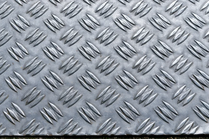 Close-up of steel diamond plate surface with raised diamond pattern filling the frame