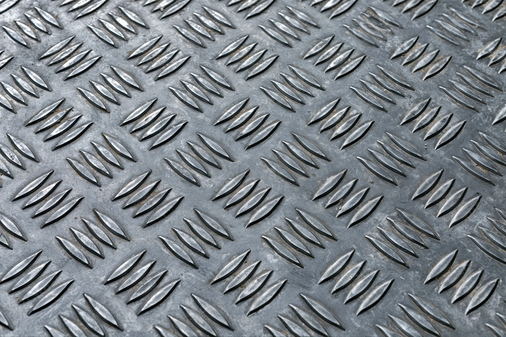 Close-up of steel diamond plate surface filling the frame with repeating embossed pattern