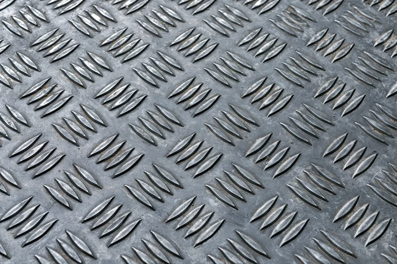 Close-up of steel diamond plate surface filling the frame with repeating embossed pattern