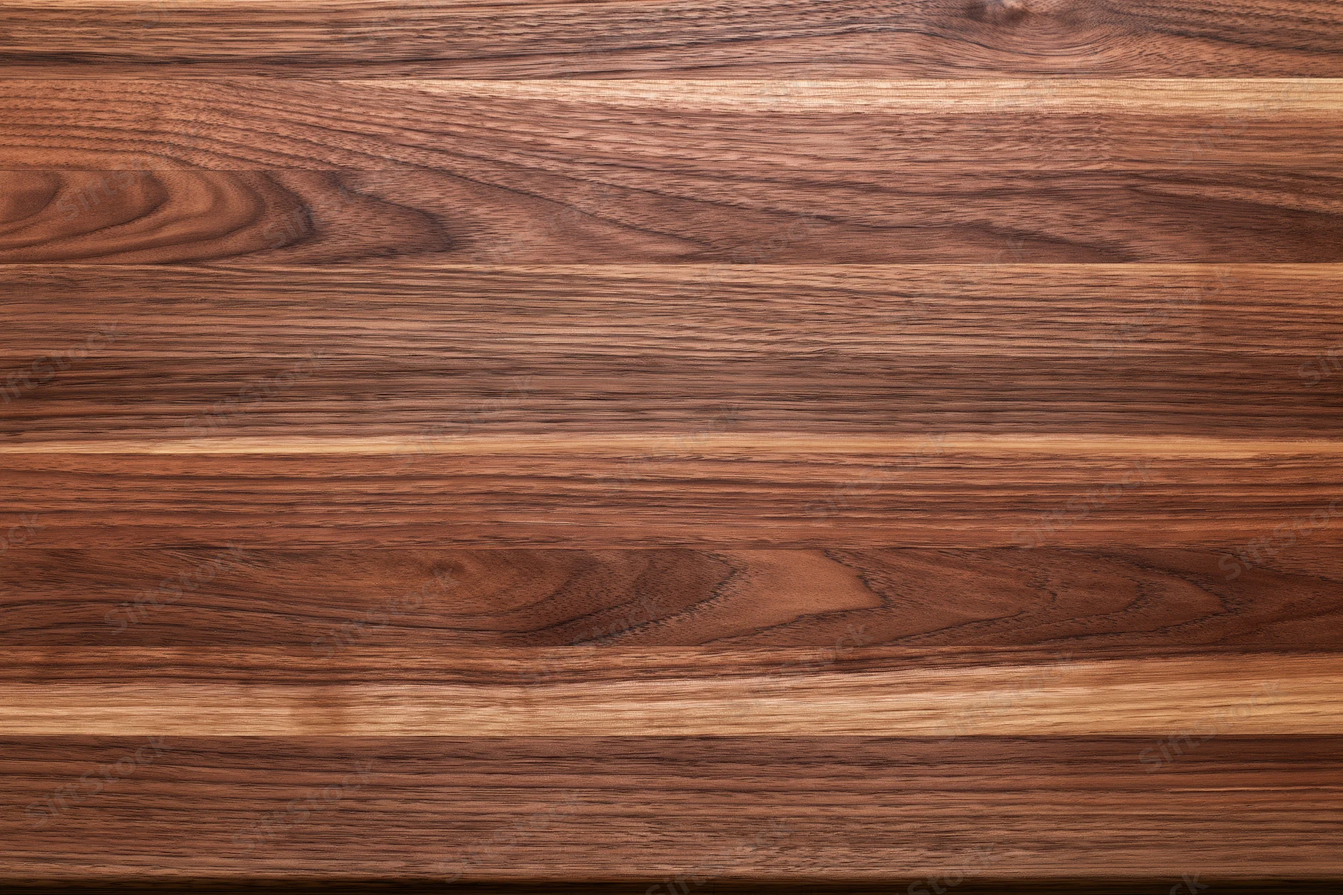 Close-up of a walnut butcher block wood surface arranged horizontally with visible grain and texture