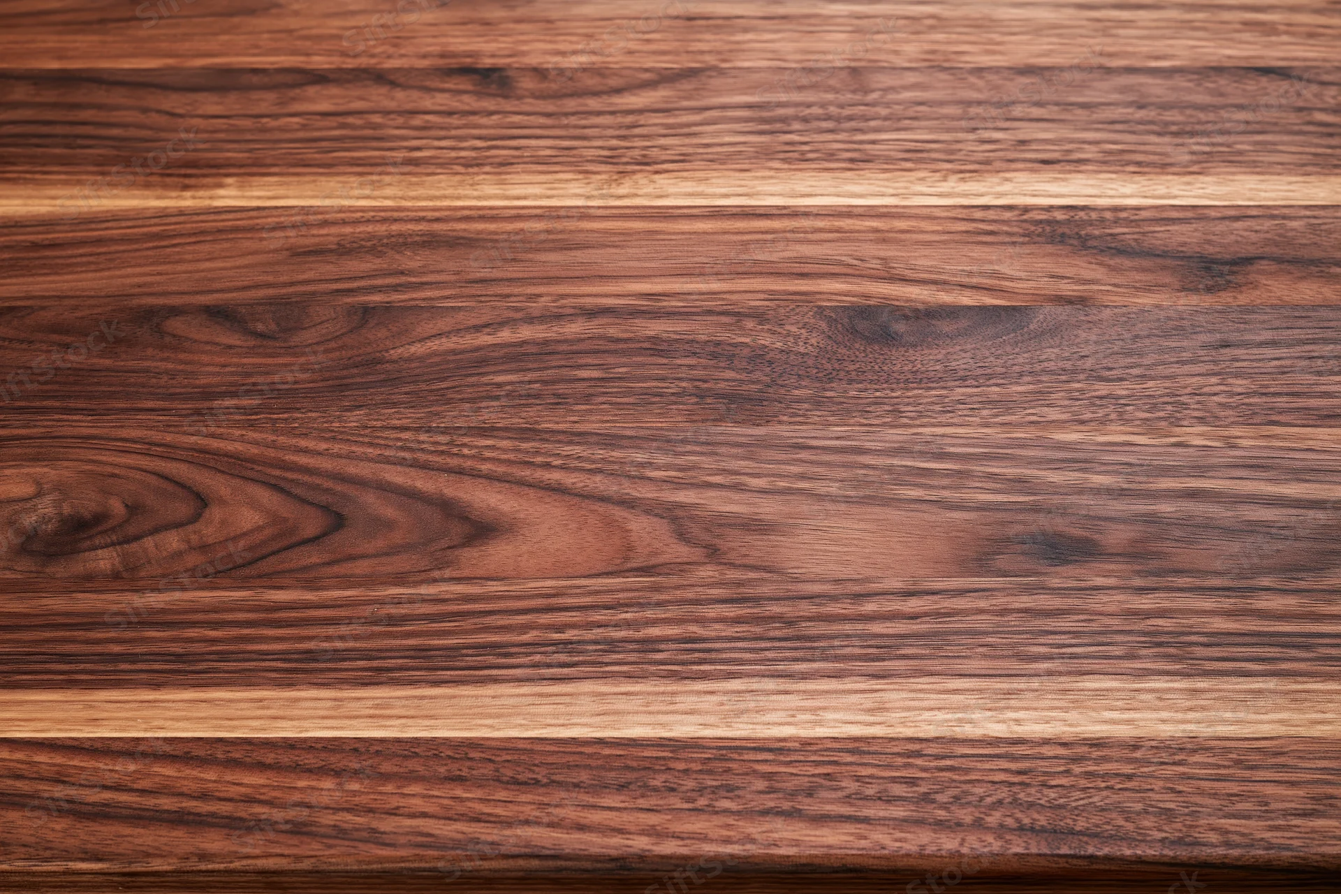 Close-up flat lay of a walnut butcher block wood surface with horizontal grain pattern and warm brown tones