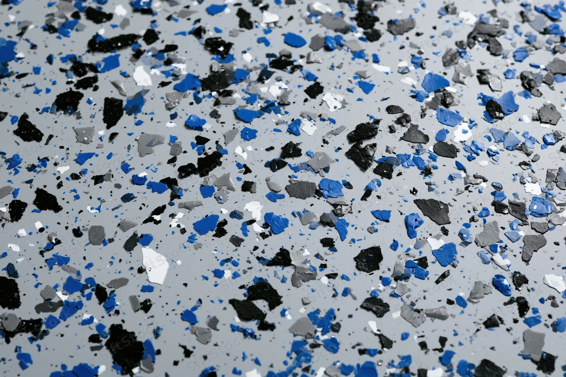 Close-up of speckled epoxy garage floor coating with blue black white and gray aggregate embedded in gray resin surface