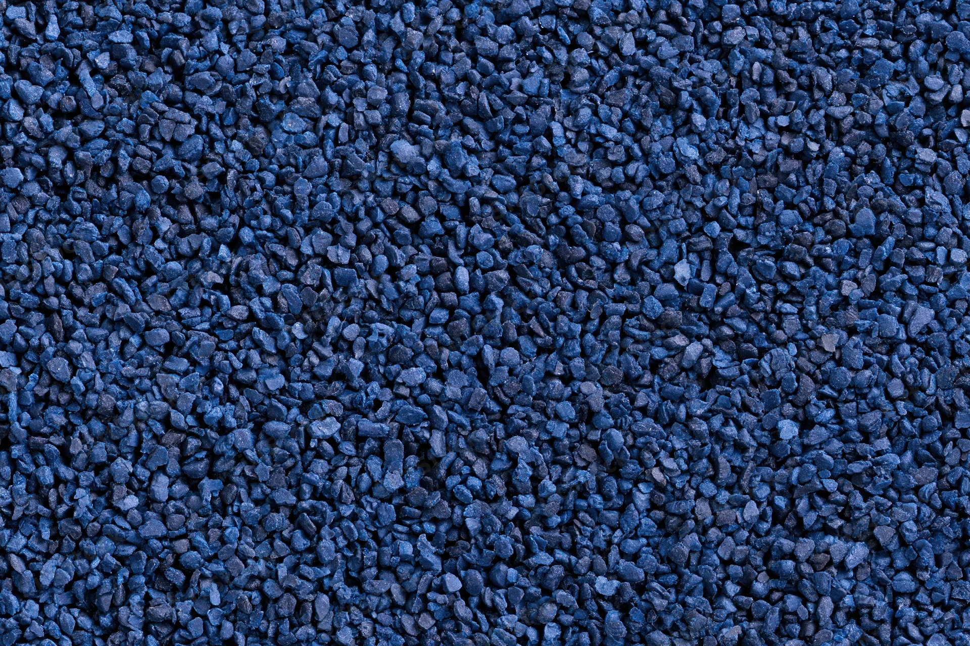 Blue rubber granules arranged in a flat lay close-up surface texture