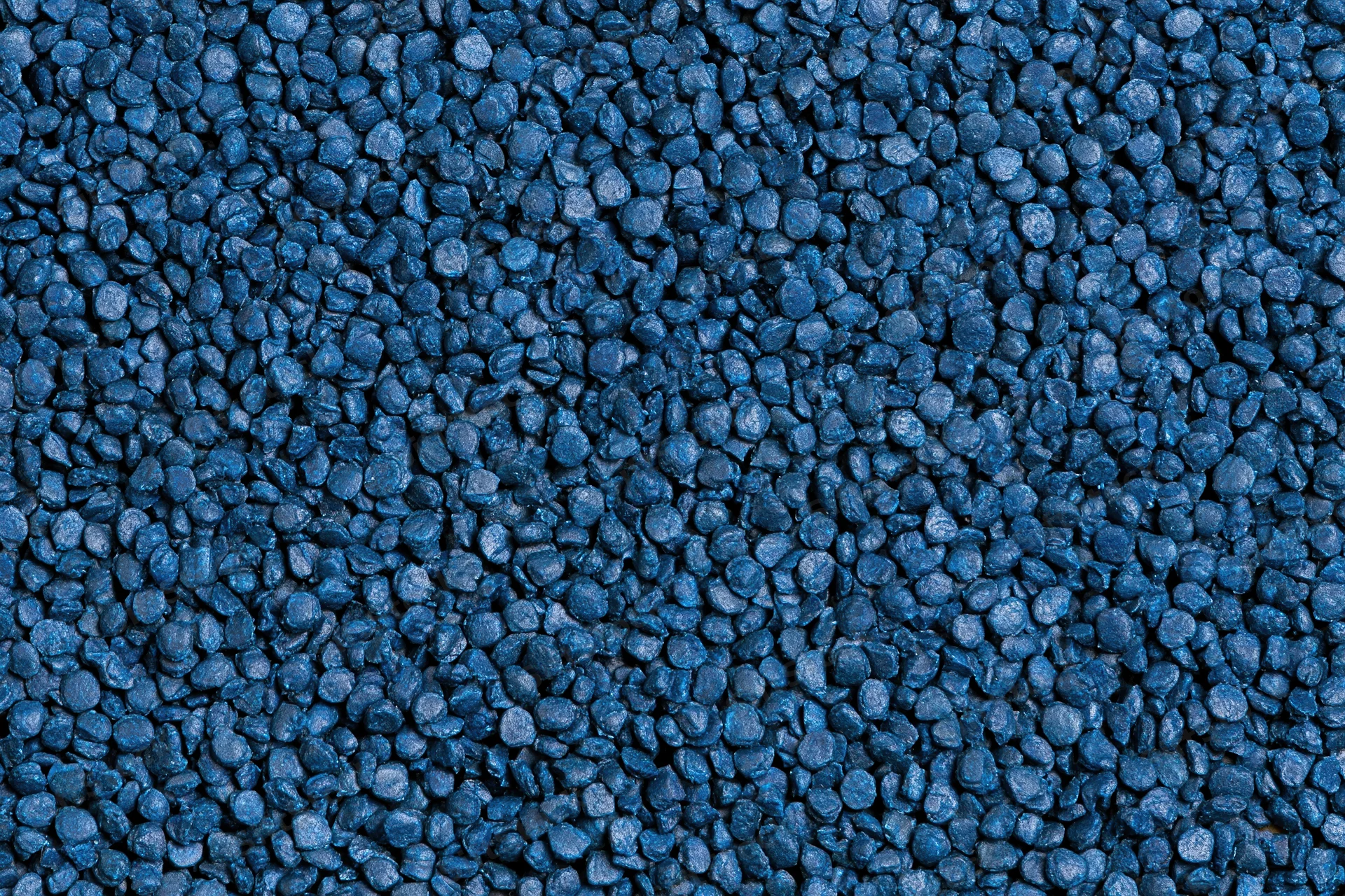 Blue rubber granules arranged in a flat lay close-up surface texture