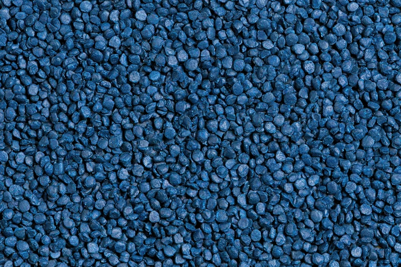 Blue rubber granules arranged in a flat lay close-up surface texture