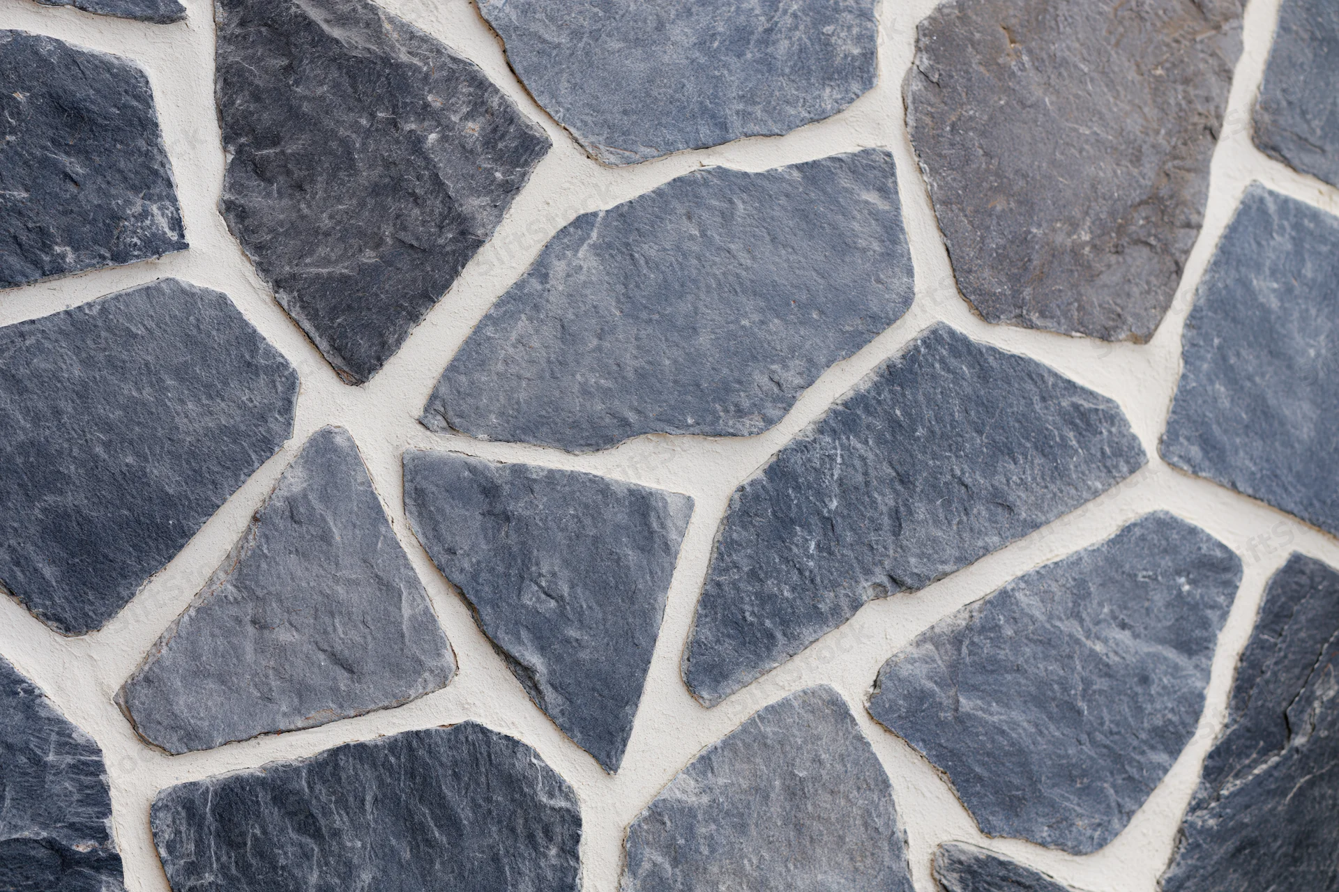 Irregular gray cobblestones arranged in a flat lay with white mortar joints