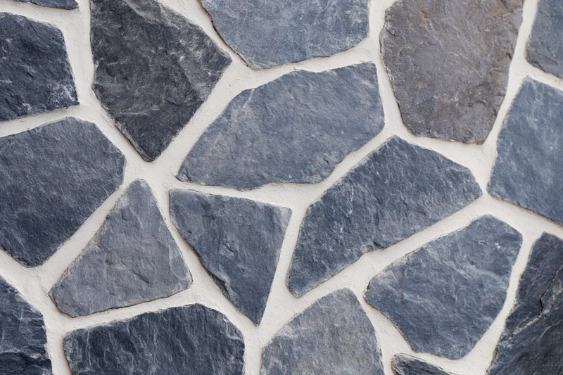Irregular gray cobblestones arranged in a flat lay with white mortar joints