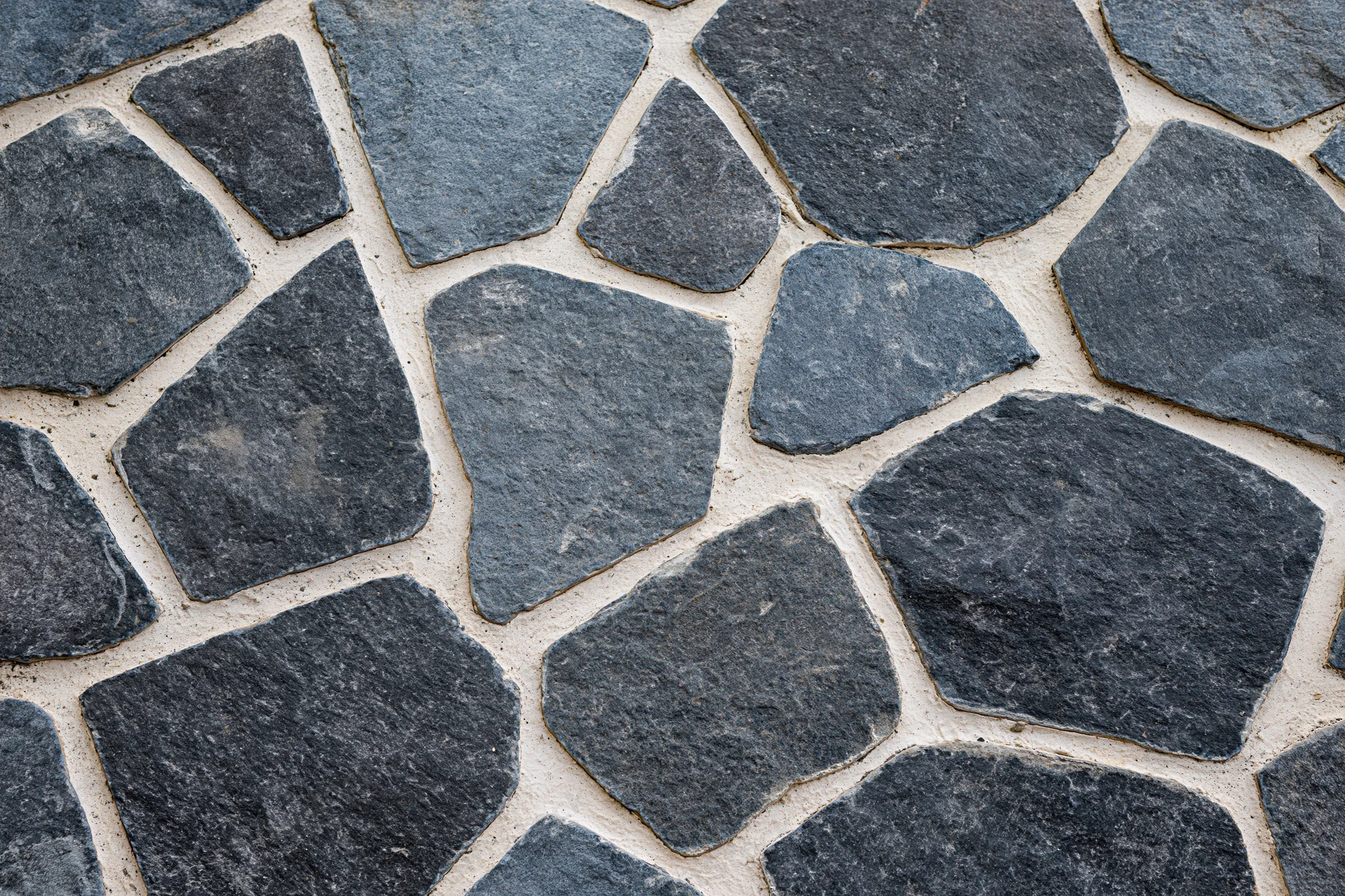 Irregular gray cobblestones arranged in a flat lay pattern for outdoor pavement