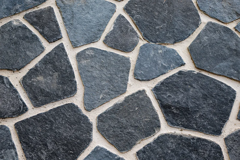 Irregular gray cobblestones arranged in a flat lay pattern for outdoor pavement