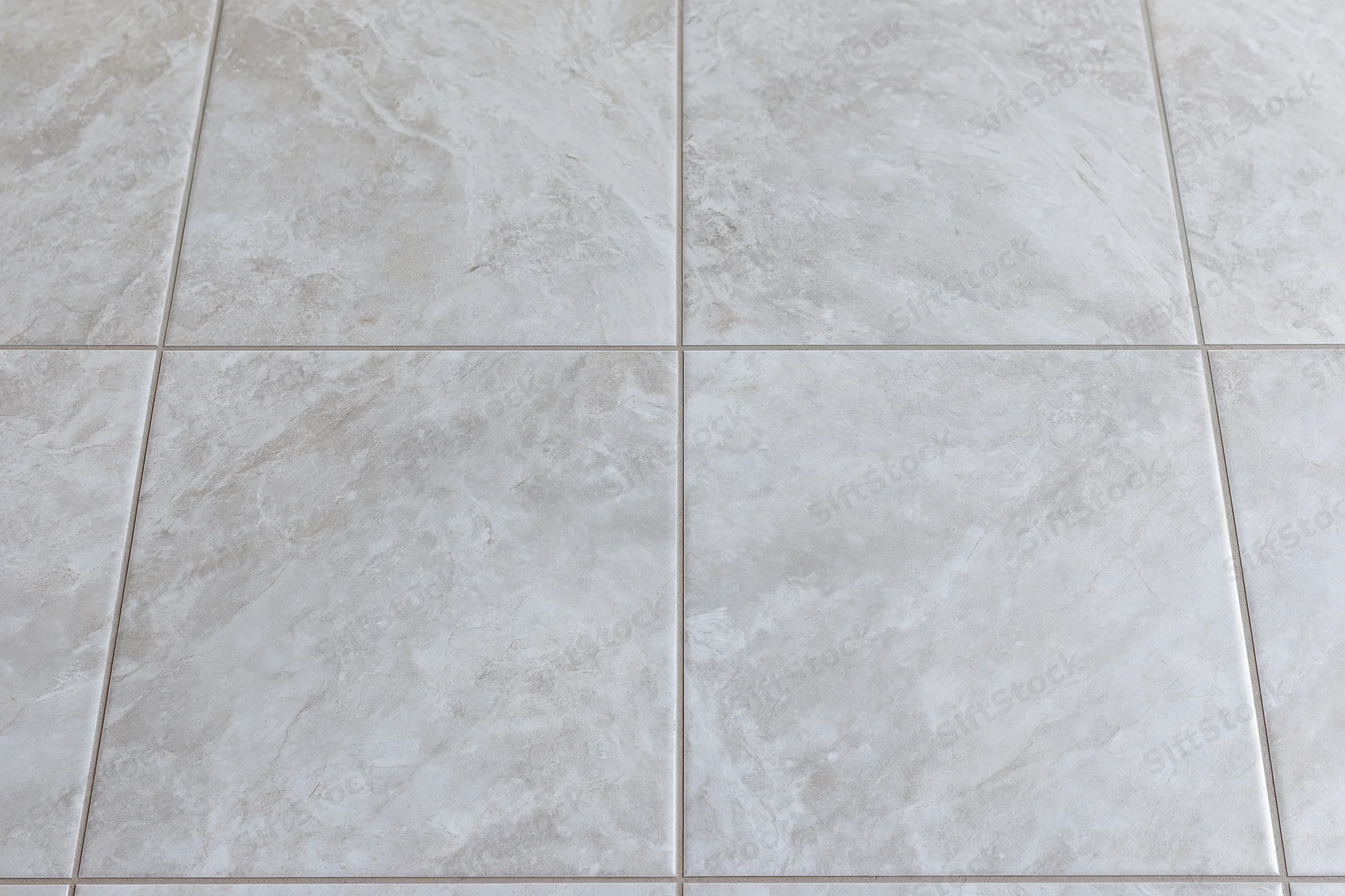 Large-format light grey ceramic floor tiles arranged in a grid pattern for interior flooring