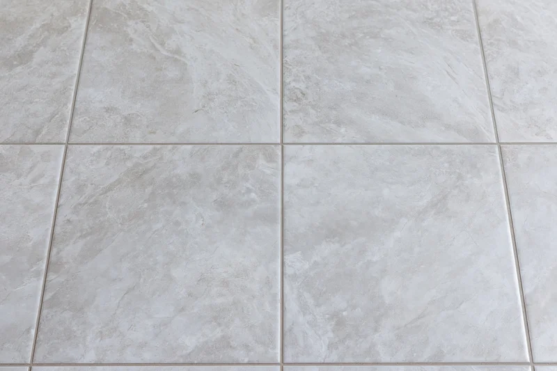 Large-format light grey ceramic floor tiles arranged in a grid pattern for interior flooring