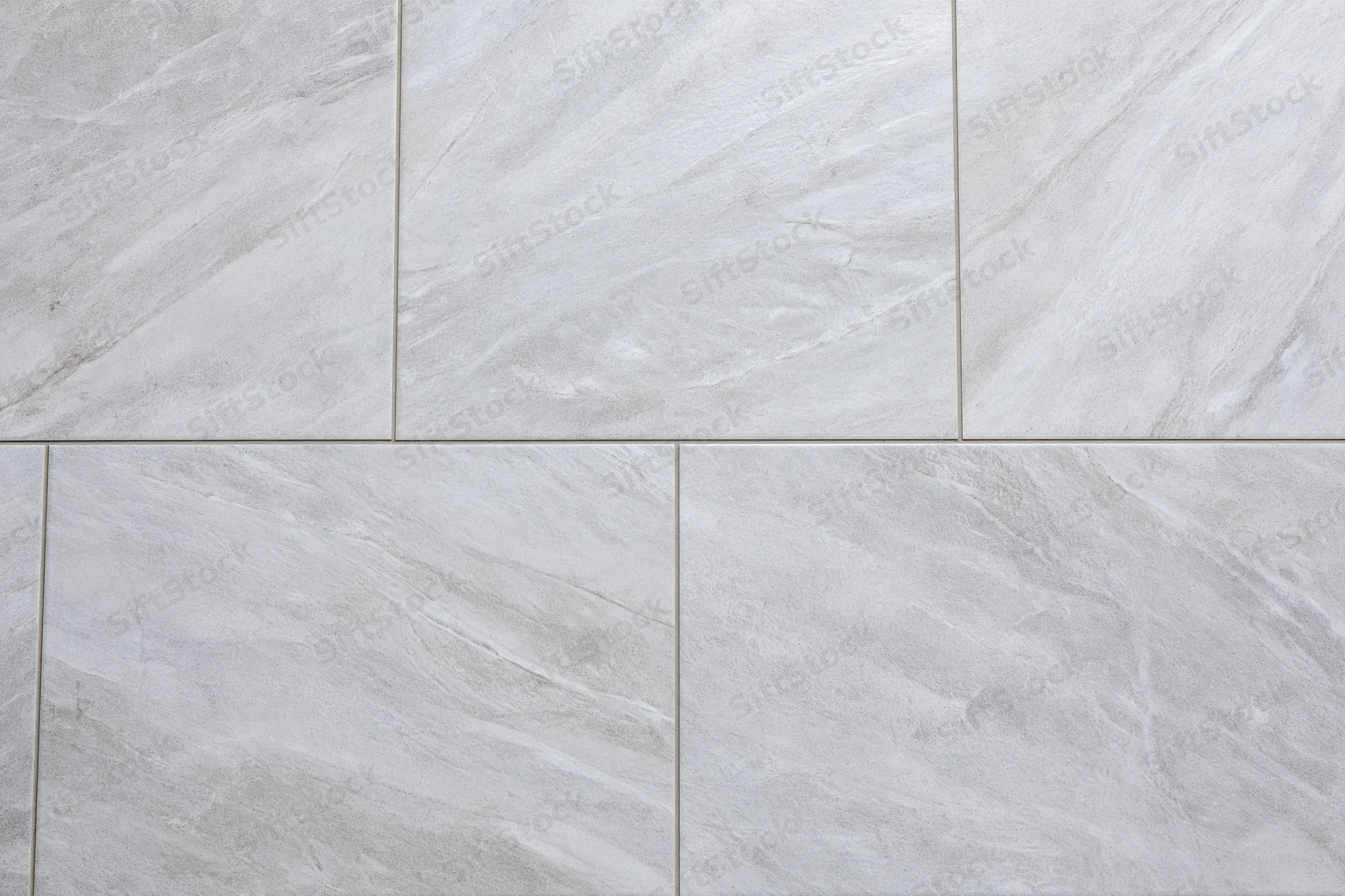 Large-format light grey ceramic floor tiles arranged in a grid pattern with visible grout lines