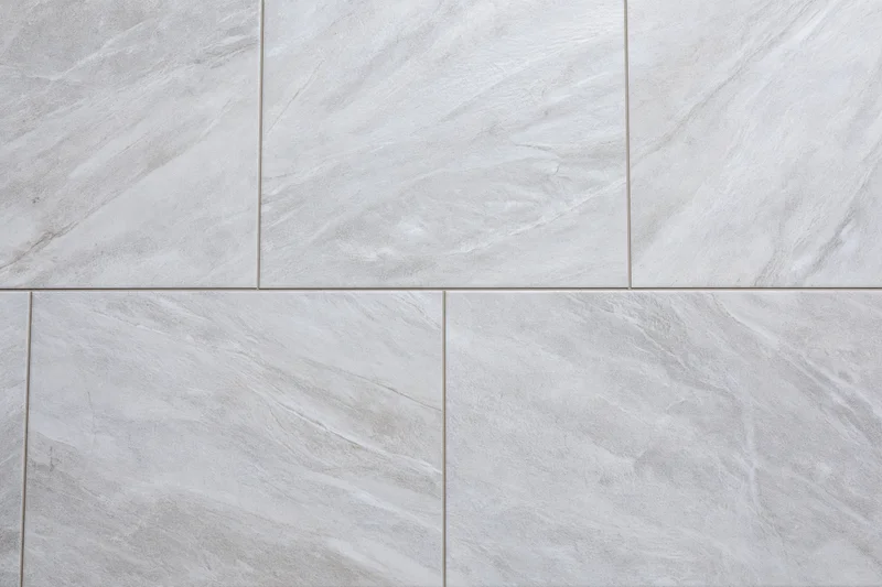 Large-format light grey ceramic floor tiles arranged in a grid pattern with visible grout lines