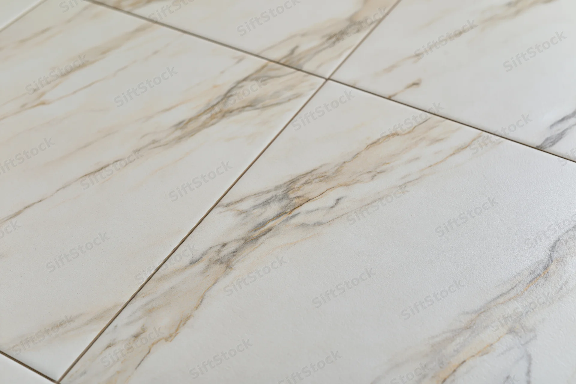Large white marble floor tiles arranged in a flat lay with veined pattern and grout lines