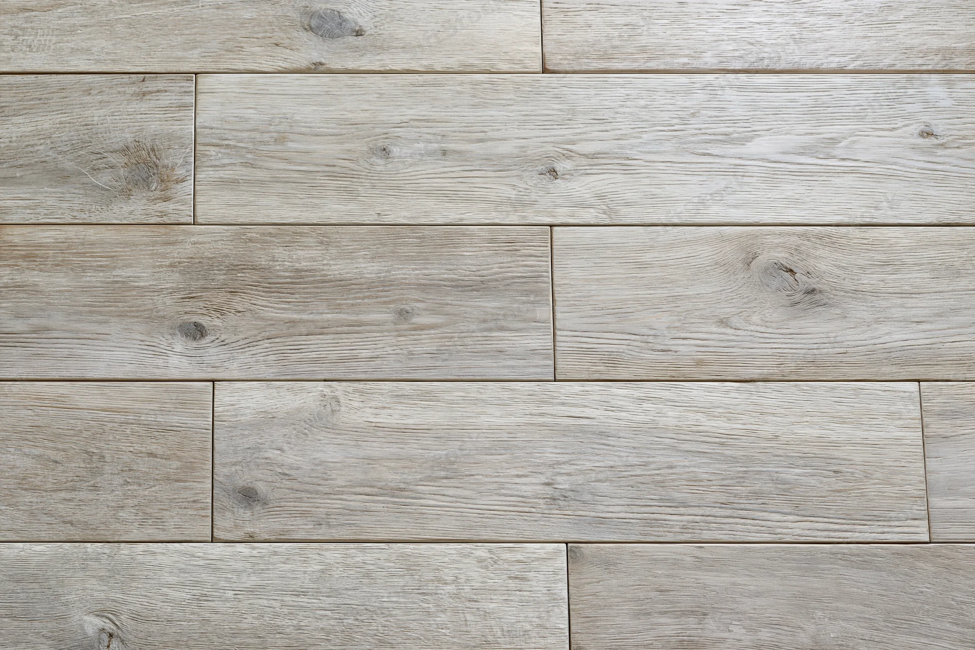 Close-up flat lay of light grey-beige hardwood floor planks arranged in staggered pattern showing natural wood grain and knots