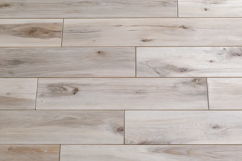 Close-up flat lay of light grey-beige hardwood floor planks arranged in staggered pattern