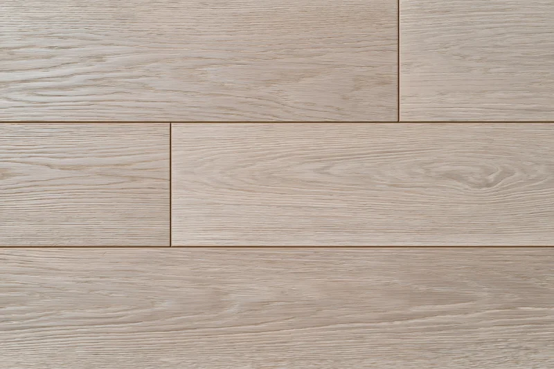 Close-up flat lay of light grey-beige oak hardwood flooring planks arranged in staggered pattern on interior floor surface